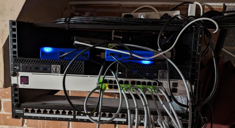 Picture of a comms rack with a patch panel, a unifi USW-Pro-24 switch, two Dell Optiplex 3040M computers, two external hard drives and a Raspberry Pi.