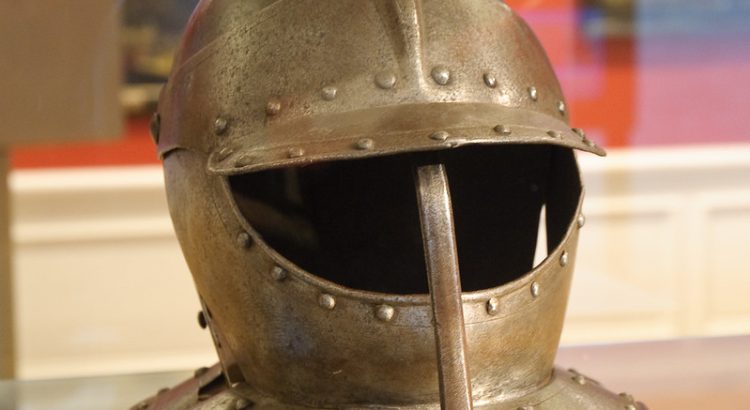 A medieval helm in gold on a bench at a museum