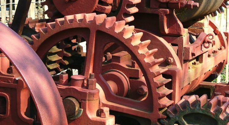 A colour photograph of a series of cogs and gears interlinked to create a machine