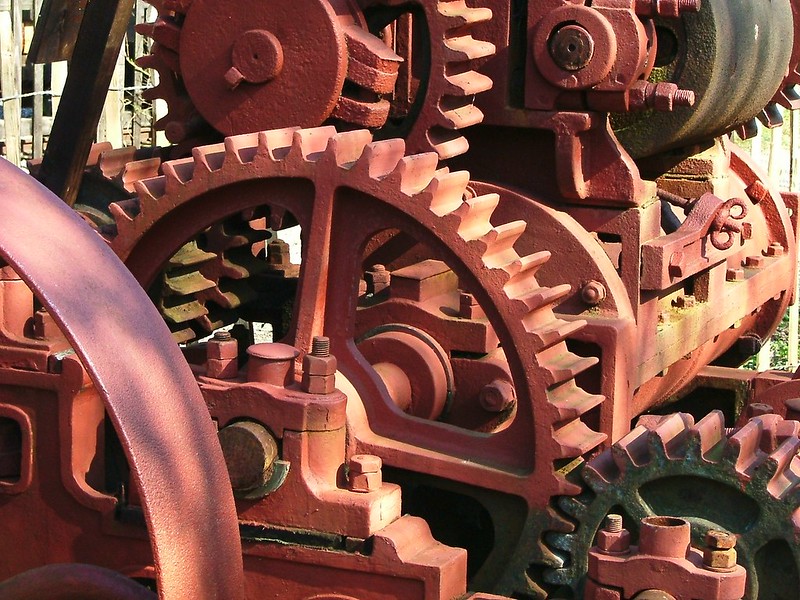 A colour photograph of a series of cogs and gears interlinked to create a machine